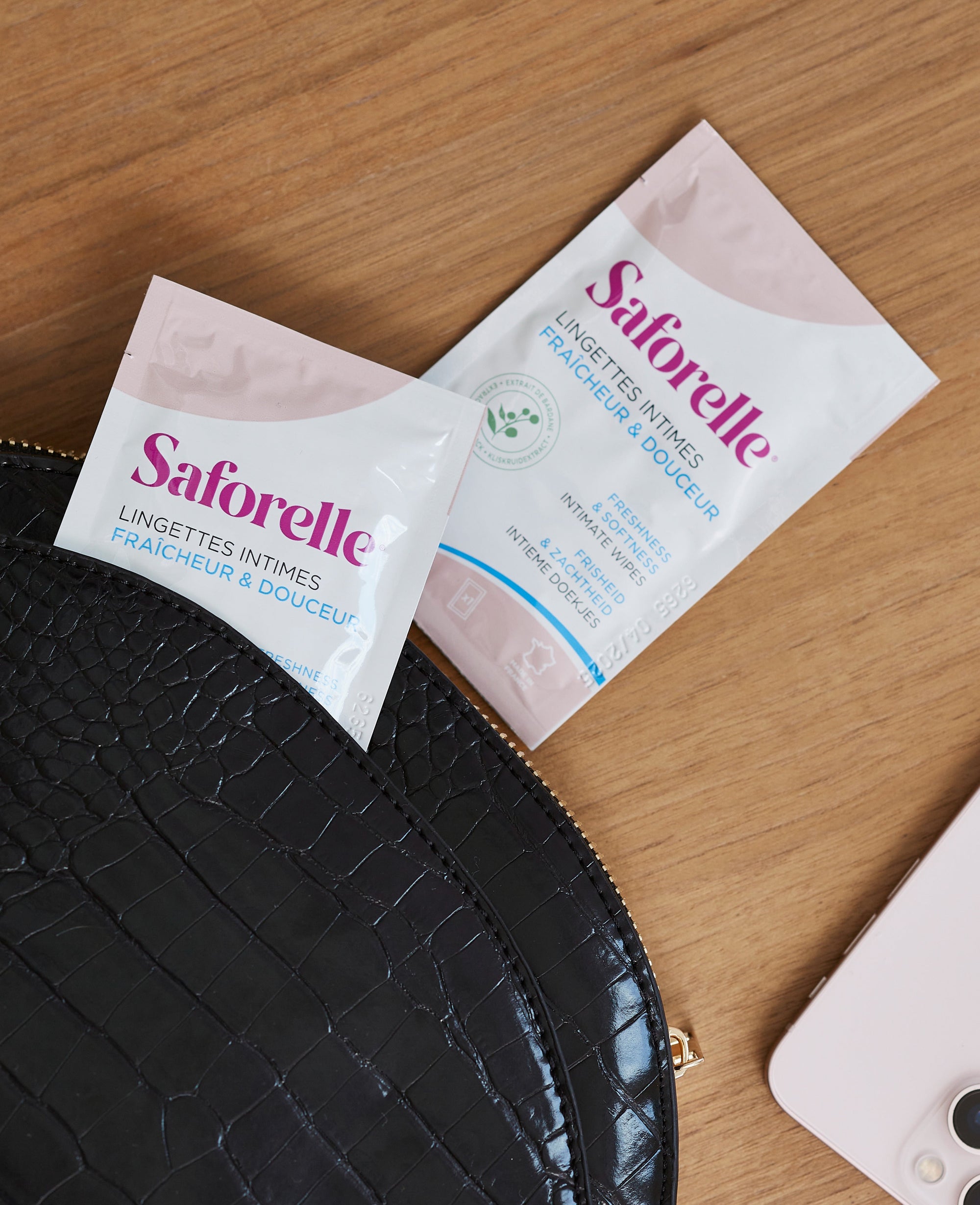 Deux sachets individuels de lingettes intimes Saforelle fraîcheur &amp; douceur posés sur une trousse, 