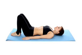 Vrouw liggend met gebogen knieën op yogamat